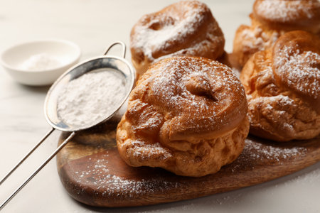 Delicious profiteroles with powdered sugar on wooden board, closeupの写真素材
