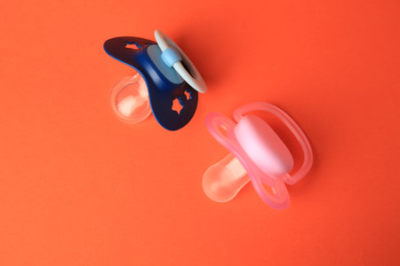 Colorful baby pacifiers on orange background, flat layの写真素材