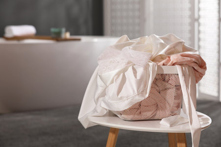 Laundry basket filled with clothes on table in bathroom, closeup. Space for textの写真素材
