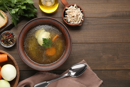 Delicious chicken bouillon and ingredients on wooden table, flat lay. Space for textの写真素材