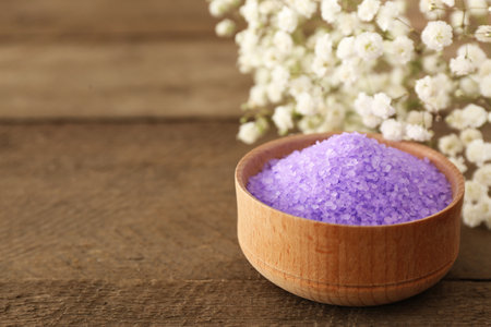 Purple sea salt and beautiful flowers on wooden table, closeup. Space for textの写真素材