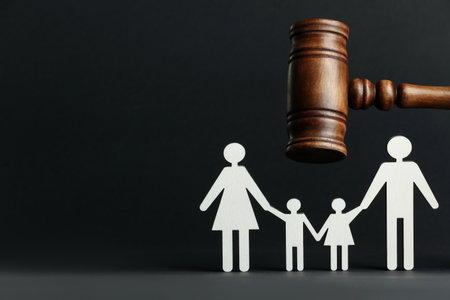 Divorce concept. Paper figures of family and wooden gavel on black background. Space for textの写真素材