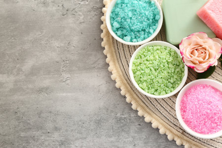 Different types of aromatic sea salt and beautiful flower on gray textured table, top view. Space for textの写真素材