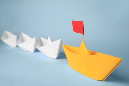 Group of paper boats following yellow one on light blue background. leadership conceptの写真素材