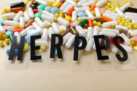 Word Herpes and different pills on wooden table, above view. Space for textの写真素材