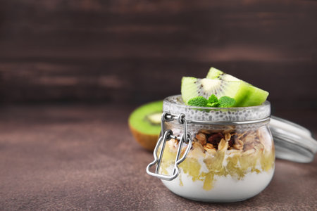 Delicious dessert with kiwi and chia seeds on brown table, closeup. Space for textの写真素材