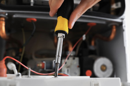 Man repairing gas boiler with screwdriver, closeupの写真素材