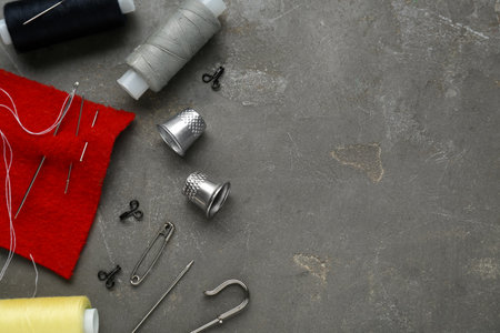 Flat lay composition with thimbles and different sewing tools on gray table. Space for textの写真素材