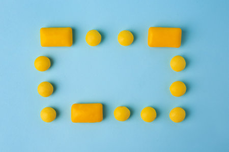Frame made of tasty chewing gums on light blue background, flat lay, Space for textの写真素材