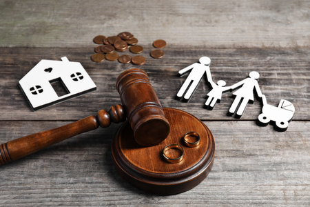 Divorce concept. Gavel, wedding rings and paper cutout of family on wooden tableの写真素材