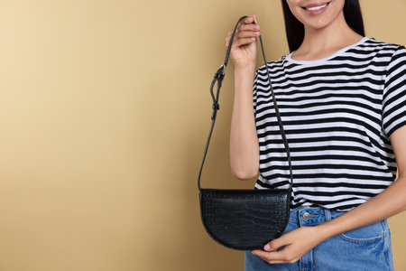 Woman with stylish bag on beige background, closeup. Space for textの写真素材