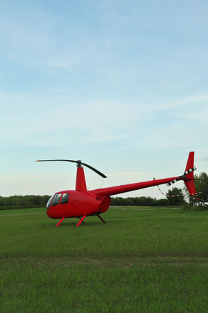 Modern red helicopter on green grass outdoorsの写真素材