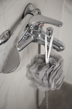 Gray shower puff hanging on faucet in bathroom, closeupの写真素材
