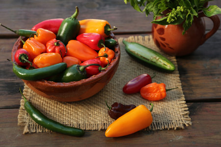 Many different ripe chili peppers on wooden tableの写真素材