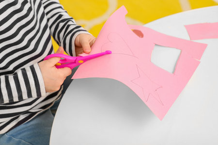 Girl cutting pink paper at desk in room, closeup. home workplaceの写真素材