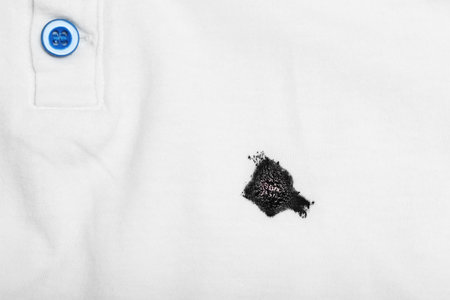 Stain of black ink on white shirt, top view. Space for text