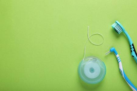 Flat lay composition with dental floss and different teeth care products on green background, space for textの写真素材