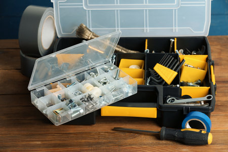 Plastic boxes with different furniture fittings and tools on wooden tableの写真素材