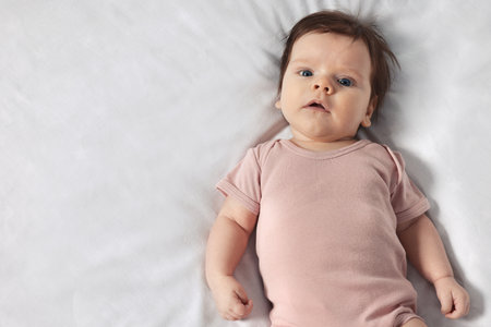 Cute little baby on cozy bed, top view. Space for text
