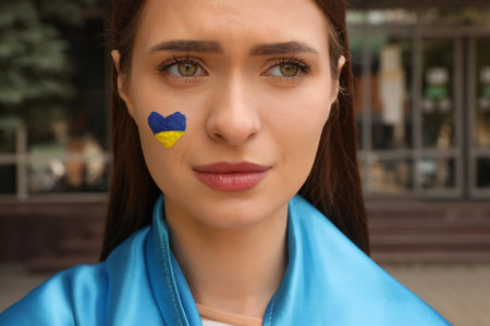 Young woman with Ukrainian flag outdoors, closeupの写真素材