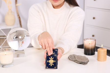 Soothsayer predicting the future with tarot cards at table indoors, closeup