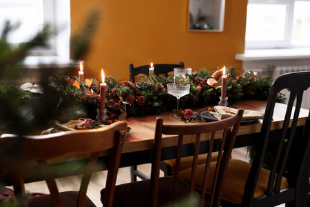 Dining table with burning candles and Christmas decor in stylish room. interior designの写真素材