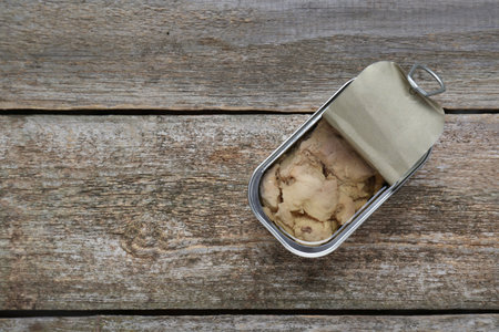 Open tin can of tasty cod liver on wooden table, top view. Space for textの写真素材