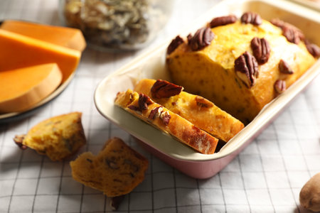 Delicious pumpkin bread with pecan nuts on tablecloth, closeup