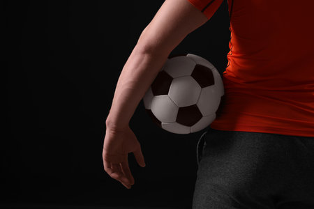 Athletic man with soccer ball on black background, closeup. Space for textの写真素材