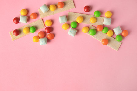 Different tasty chewing gums on pink background, flat lay. Space for text