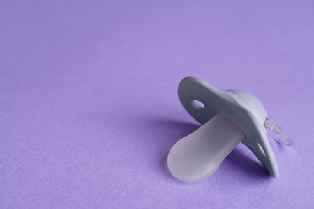 New baby pacifier on purple background, closeup. Space for textの写真素材