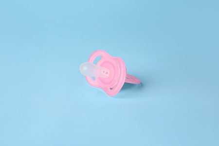 One new baby pacifier on light blue background