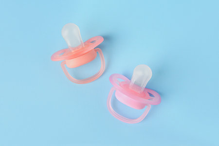 New baby pacifiers on light blue background, flat layの写真素材