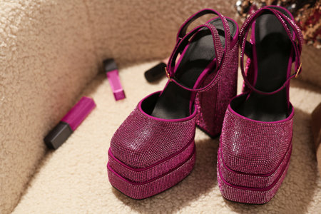 New pink high heeled shoes with platform and makeup products on soft armchair, closeupの写真素材