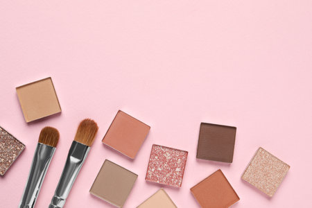 Different beautiful eye shadows and makeup brushes on pink background, flat lay. Space for textの写真素材
