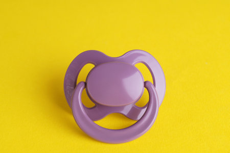 New cute baby pacifier on yellow backgroundの写真素材