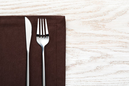 Fork, knife and napkin on white wooden table, top view with space for text. Stylish shiny cutlery setの写真素材
