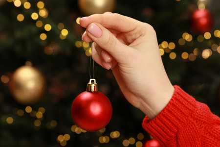Woman holding Christmas ball against blurred lights, closeupの写真素材
