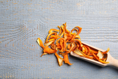 Scoop with dry orange peels on wooden table, flat lay. Space for textの写真素材