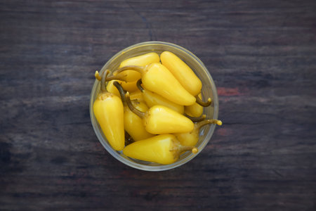 Bowl of pickled yellow jalapeno peppers on wooden table, top viewの写真素材