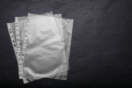 Punched pockets on black table, flat lay. Space for textの写真素材