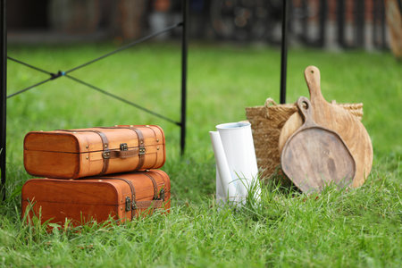 Suitcases, boards and wicker basket on green grass in yard. Garage saleの写真素材
