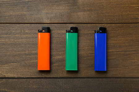 Colorful plastic cigarette lighters on wooden table, flat layの写真素材