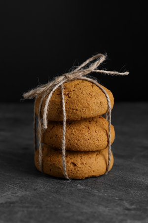 Delicious oatmeal cookies tied with twine on gray table