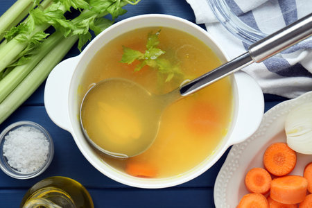 Delicious chicken bouillon and ingredients on blue wooden table, flat layの写真素材