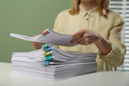 Woman stacking documents at white table in office, closeupの写真素材