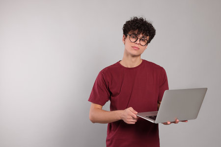 Handsome young man using laptop on light gray background. Space for textの写真素材