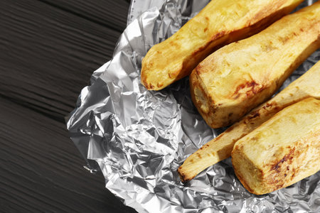 Tasty baked parsnips on black wooden table, above view. Space for textの写真素材