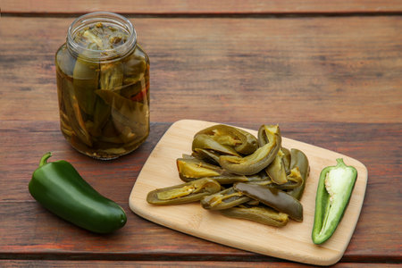 Fresh and pickled green jalapeno peppers on wooden tableの写真素材