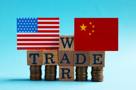 USA and China flags, coins and phrase Trade war made of wooden cubes on light blue backgroundの写真素材